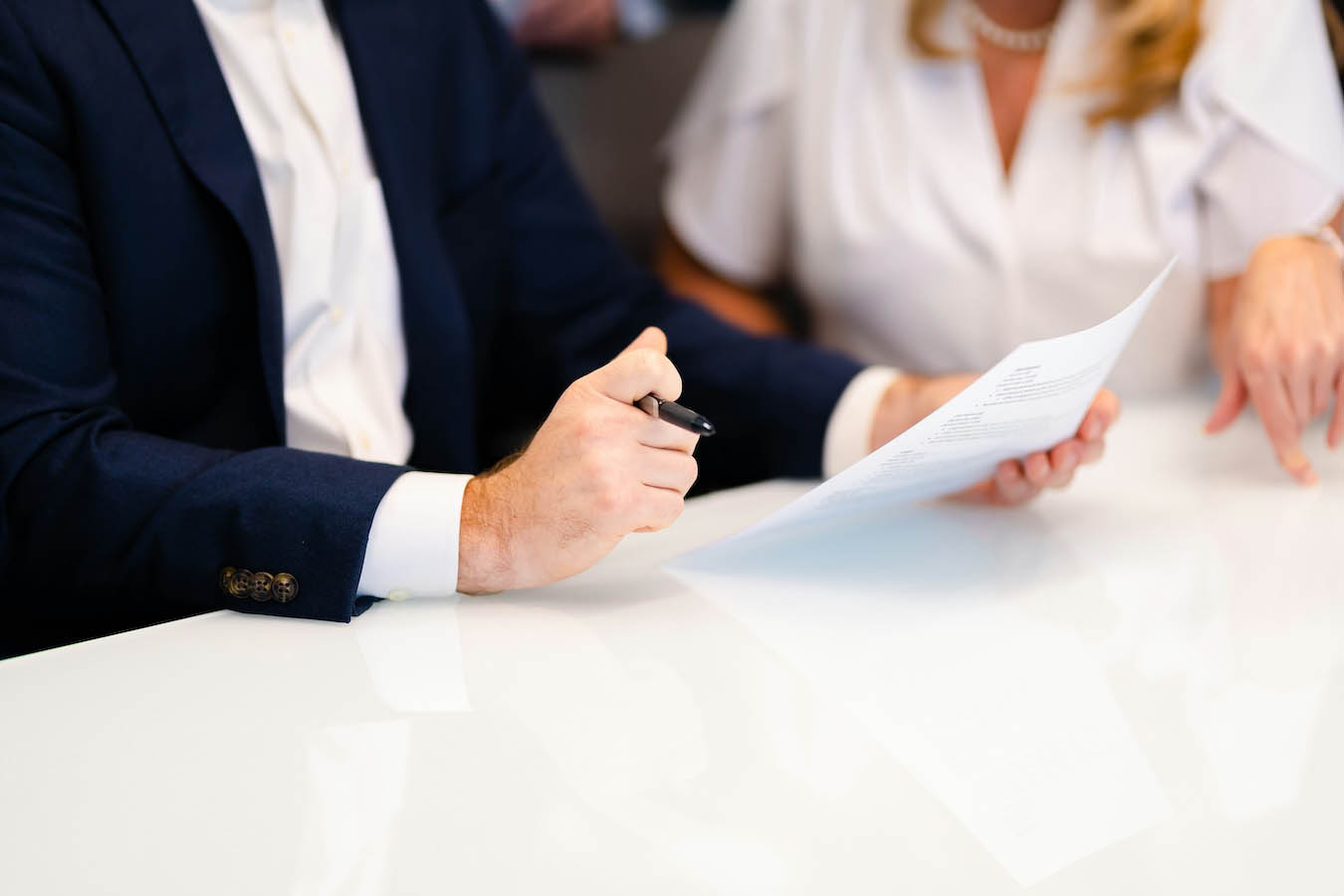 Man and woman in professional attire reviewing a document at large white desk in meeting room hire space